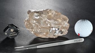 Picture of 2,488 carat rough diamond next to tweezers, a golf ball, and a loupe
