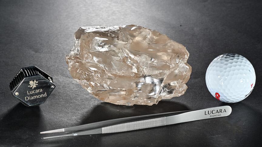 Picture of 2,488 carat rough diamond next to tweezers, a golf ball, and a loupe