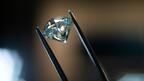 Stock image of a polished diamonds being held by tweezers