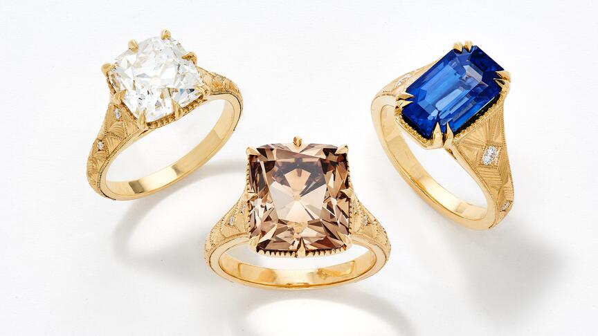 From left to right, a 4.05-carat old mine-cut white diamond ring, an 8.66-carat old mine-cut fancy dark yellowish brown diamond ring, and a 5.48-carat octagonal step-cut vivid blue sapphire ring, each set in 18-karat yellow gold with round diamond accents. Artifex White Diamond, Fancy Dark Yellowish Brown Diamond, and Blue Sapphire Rings