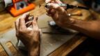 Bench jeweler holding a ring and a tool
