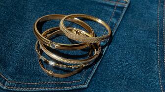 Stack of gold bangles on denim