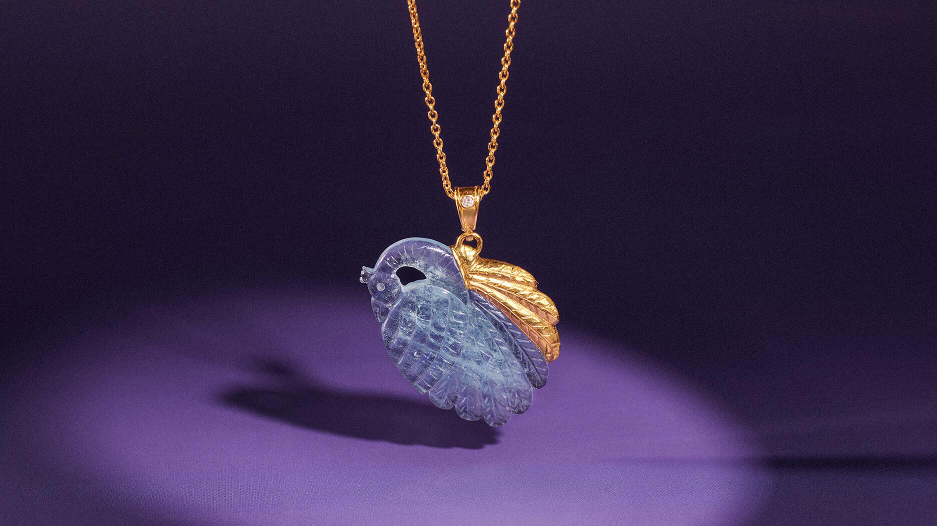 A peacock carved from aquamarine, capped with 24-karat yellow gold, and attached to a 22-karat yellow gold chain via an 18-karat yellow gold bale featuring a brilliant-cut diamond ($6,680). Gurhan Crown Gold Aquamarine Peacock